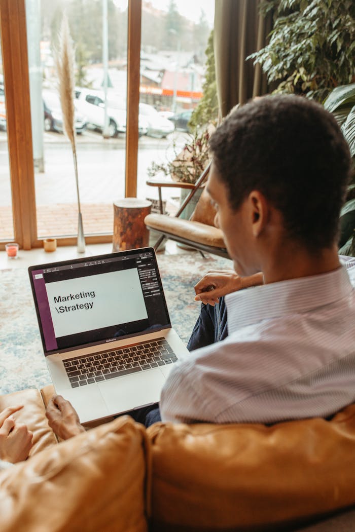 A man reviews a marketing strategy on his laptop in a cozy indoor setting.